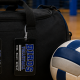 A black duffel bag with a hanging tag reading 'BIRDS VOLLEYBALL RISE, RALLY, REPEAT.' sits on a wooden floor next to a blue and white volleyball in a gym setting.
